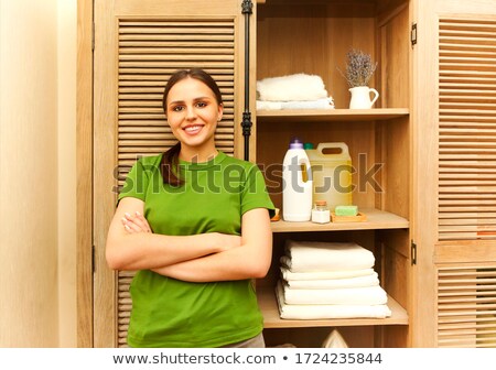 Foto d'archivio: Young Woman Folding Shirt With Laundry Basket