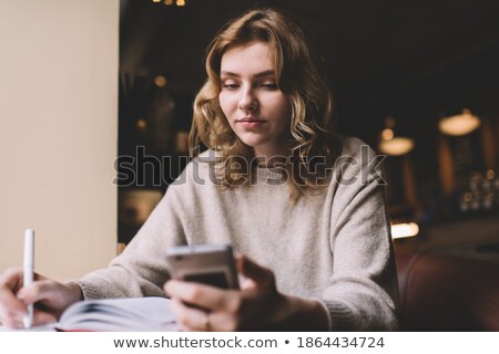Stockfoto: Businesswoman With Cellphone And Writing In Organizer In A Cafe