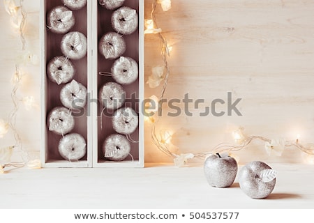 Foto stock: Christmas Soft Home Decor Of Silver Apples And Lights Burning In Boxes On A Wooden White Backgroun