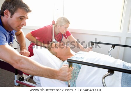 Foto stock: Three Doctors Pushing A Patient In Bed