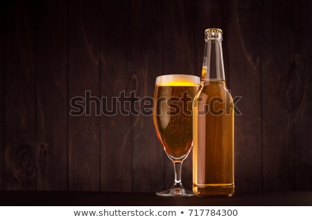 [[stock_photo]]: Transparent Beer Bottle And Glass Tulip With Golden Lager On Dark Brown Wood Board Copy Space Mock