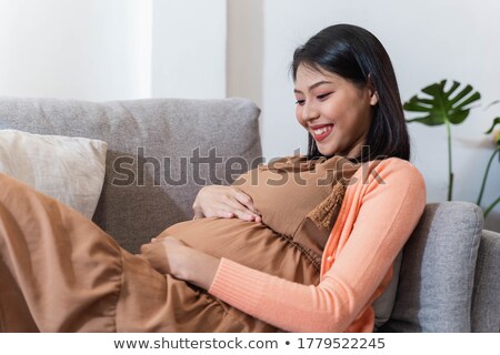 [[stock_photo]]: Happy Pregnant Woman With Headphones At Home