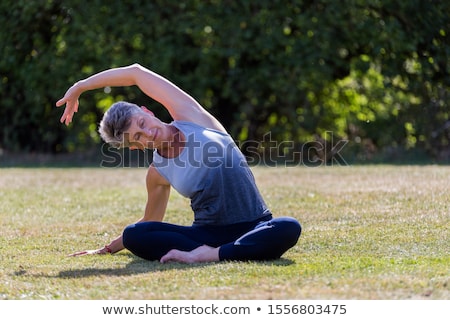 Stockfoto: Senior Woman Doing Yoga And Legs Stretching In The Park