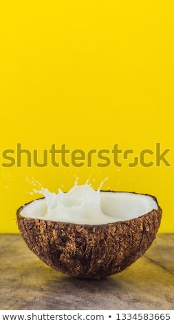 Сток-фото: Coconut Fruit And Milk Splash Inside It On Yellow Background Vertical Format For Instagram Mobile St