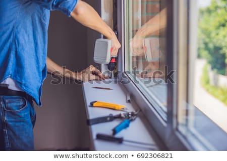 Stock photo: Man In A Blue Shirt Does Window Installation