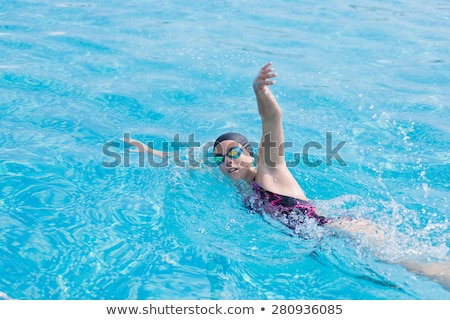 Foto stock: Young Girl In Goggles And Cap Swimming Crawl Stroke Style