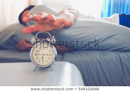 Foto d'archivio: Woman Sleeping On Bed Turning Off Alarm Clock