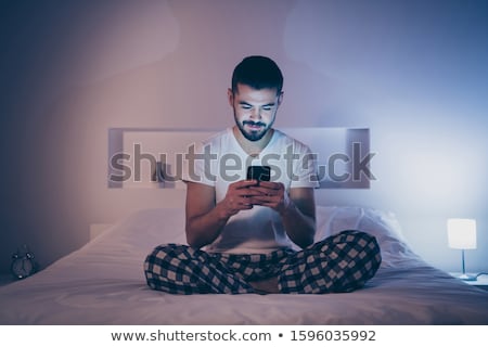 Stock fotó: Young Man Using His Smartphone In Bed