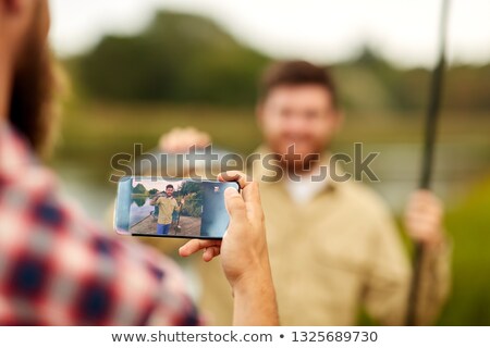 Stok fotoğraf: Friend Photographing Fisherman By Smartphone