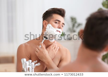 Foto stock: Attractive Caucasian Man Shaving In The Bathroom At Home