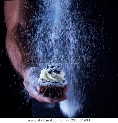 ストックフォト: Cupcake In Mans Hand And The Pouring Icing Sugar