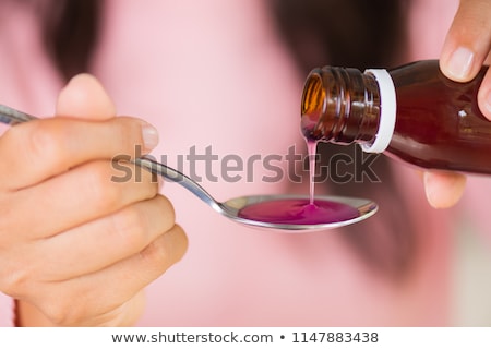 Сток-фото: Woman Pouring Syrup From Bottle To Medicine Cup
