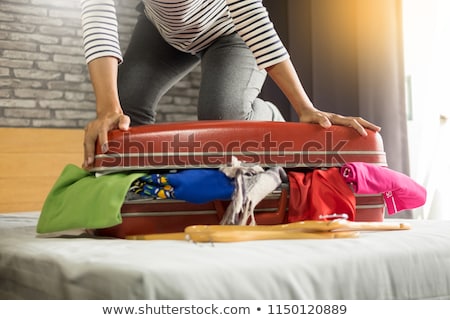 Stockfoto: Woman Trying To Fit All Clothing To Packing Her Red Suitcase Be