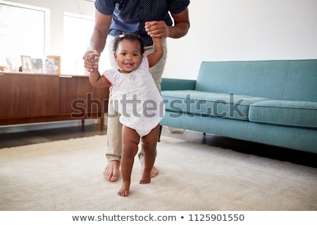 Foto d'archivio: Father Helping Baby Daughter With Walking At Home