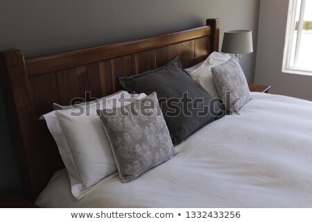 Stock fotó: Side View Of Table Lamp And Diverse Pillows Arranged On A Bed In Bedroom At Home