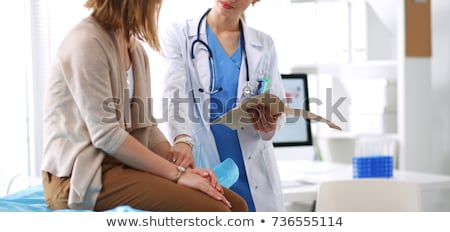 Stock foto: Doctor And Patient Discuss Something Sit At Table In Clinic Female Cardiologist In Eyewear Gives M