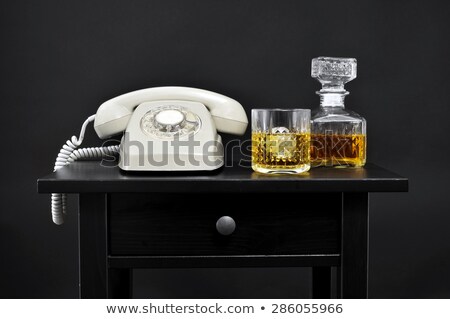 Foto stock: A Retro Telephone A Bottle And A Glass With Liquor On A Table