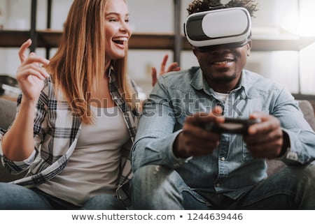 Foto stock: Laughing Young Lady Wearing Virtual Reality Device And Holding Joysticks