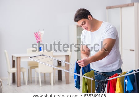 Zdjęcia stock: Smiling Man With Laundry And Drying Rack At Home