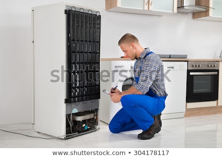 Stock fotó: Male Worker Repairing Refrigerator In Kitchen Room