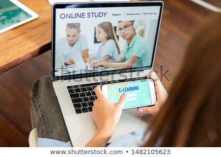 Сток-фото: Young Female Student Holding Smartphone Over Laptop Keypad