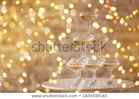 [[stock_photo]]: Sparkling Champagne Pyramid Tower Of Glasses At The Party In Front Of Golden Wall