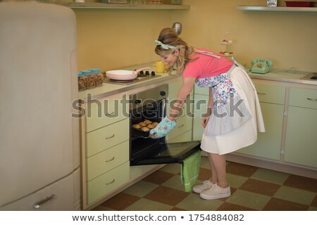 Foto d'archivio: Waitress Putting Muffins In Oven