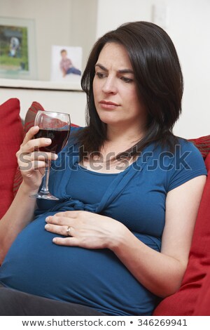 Foto stock: Concerned Pregnant Woman Drinking Glass Of Wine At Home