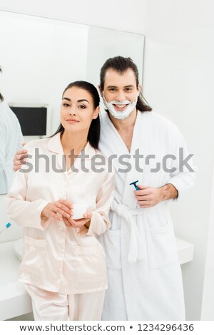 ストックフォト: Young Woman In White Bathrobe Applying Shaving Foam On Beard Of Her Husband