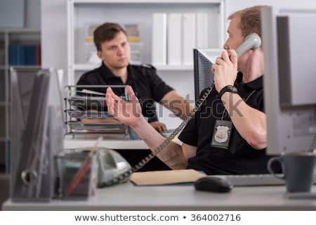 Foto stock: Police Officer Working On Desk In Station