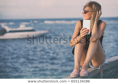 Stock fotó: Female Tourist Using Mobile Phone At Seaside On Summer Holiday