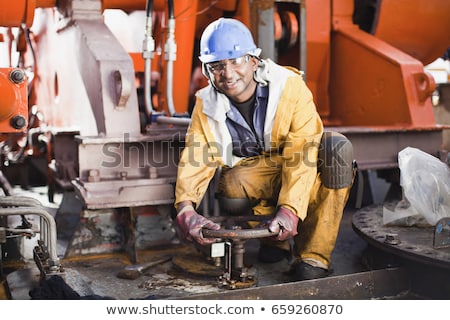 Foto stock: Worker Turning Wheel On Oil Rig
