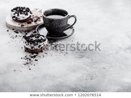 ストックフォト: Black Coffee Cup With Saucer And Doughnut With Black Cookies On Black Stone Kitchen Table Background