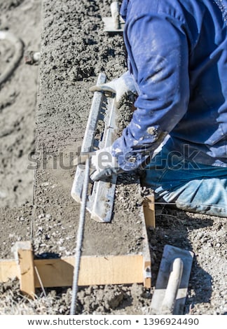Foto d'archivio: Pool Construction Worker Working With A Smoother Rod On Wet Conc