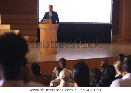 Сток-фото: Front View Of Handsome Mixed Race Businessman Giving Speech In Front Of Audience In The Auditorium