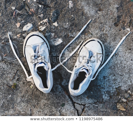 Foto stock: Top View Of Worn Gray Sneakers On White Asphalt Road