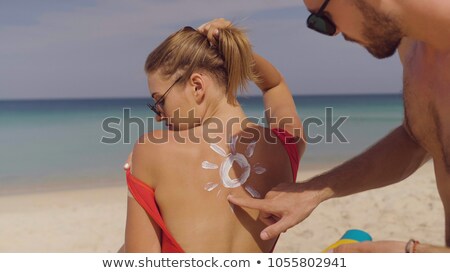 Foto stock: Couple Putting On Suntan Lotion