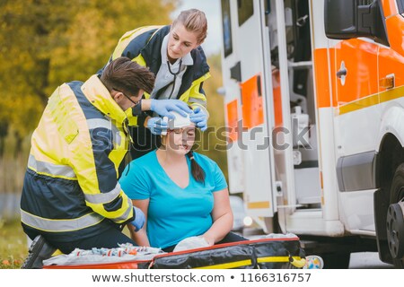 Stockfoto: Emergency Medics Dressing Head Wound Of Injured Woman