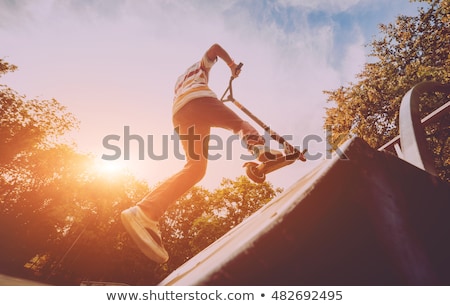 Stok fotoğraf: Boy Riding A Scooter Is Jumping At A Scooter Park