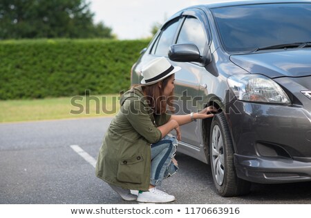 Foto stock: Girl Checking Air Pressure Of Car Tire