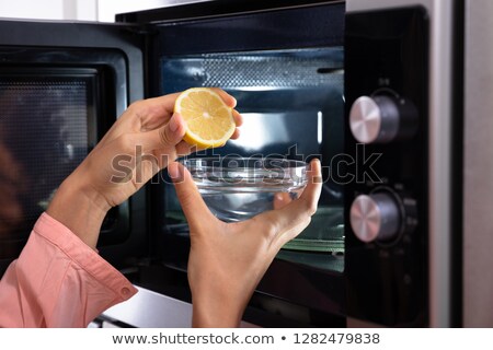 Foto d'archivio: Womans Hand Squeezing Halved Lemon In Bowl