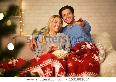 Stockfoto: Happy Couple Watching Tv At Home On Christmas