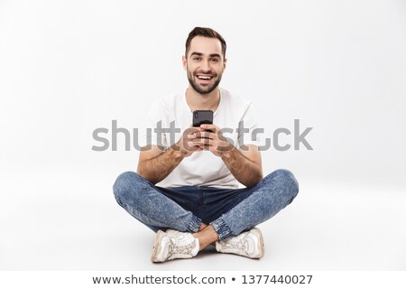 Stock fotó: Young Man Sitting On Floor With Mobile Phone