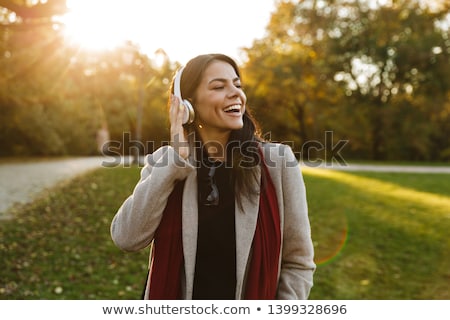 Stok fotoğraf: Young Joyful Pleased Female Listening To Music In The Park