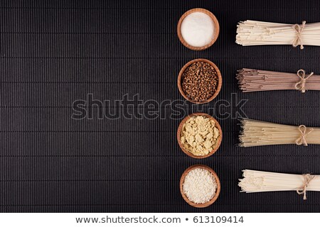 Zdjęcia stock: Raw Asian Noodles With Ingredient In Wooden Bowls On Black Striped Mat Background With Copy Space