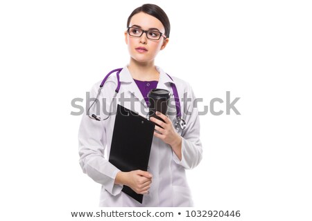 Zdjęcia stock: Young Woman Doctor With Stethoscope Holding Clipboard And Cup Of Coffee In Her Hands In White Unifor