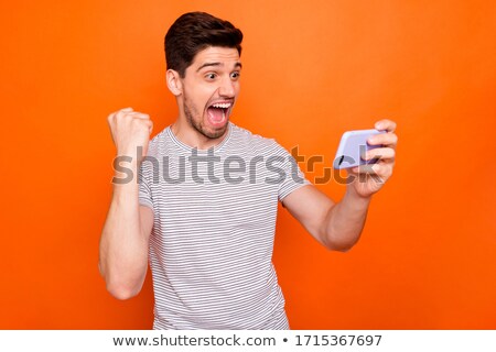 [[stock_photo]]: Image Of Joyful Man In Striped T Shirt Smiling And Holding Cell