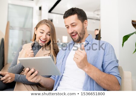 Foto d'archivio: Young Ecstatic Students In Casualwear Looking At Stuff On Touchpad Display