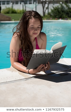 Foto stock: Girl Reading On The Edge Of Pool