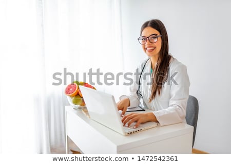 Stock fotó: Female Nutritionist Sitting In Her Working Place Showing And Offering Glass Of Pineapple Orange Appl
